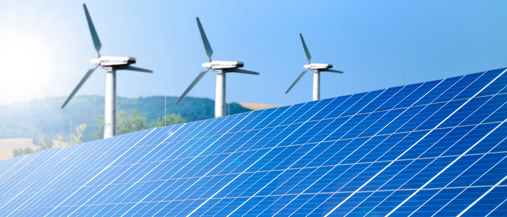 Photovoltaikanlage mit Solarmodulen und Windkraftanlagen auf einem Feld zur Darstellung erneuerbarer Energien.