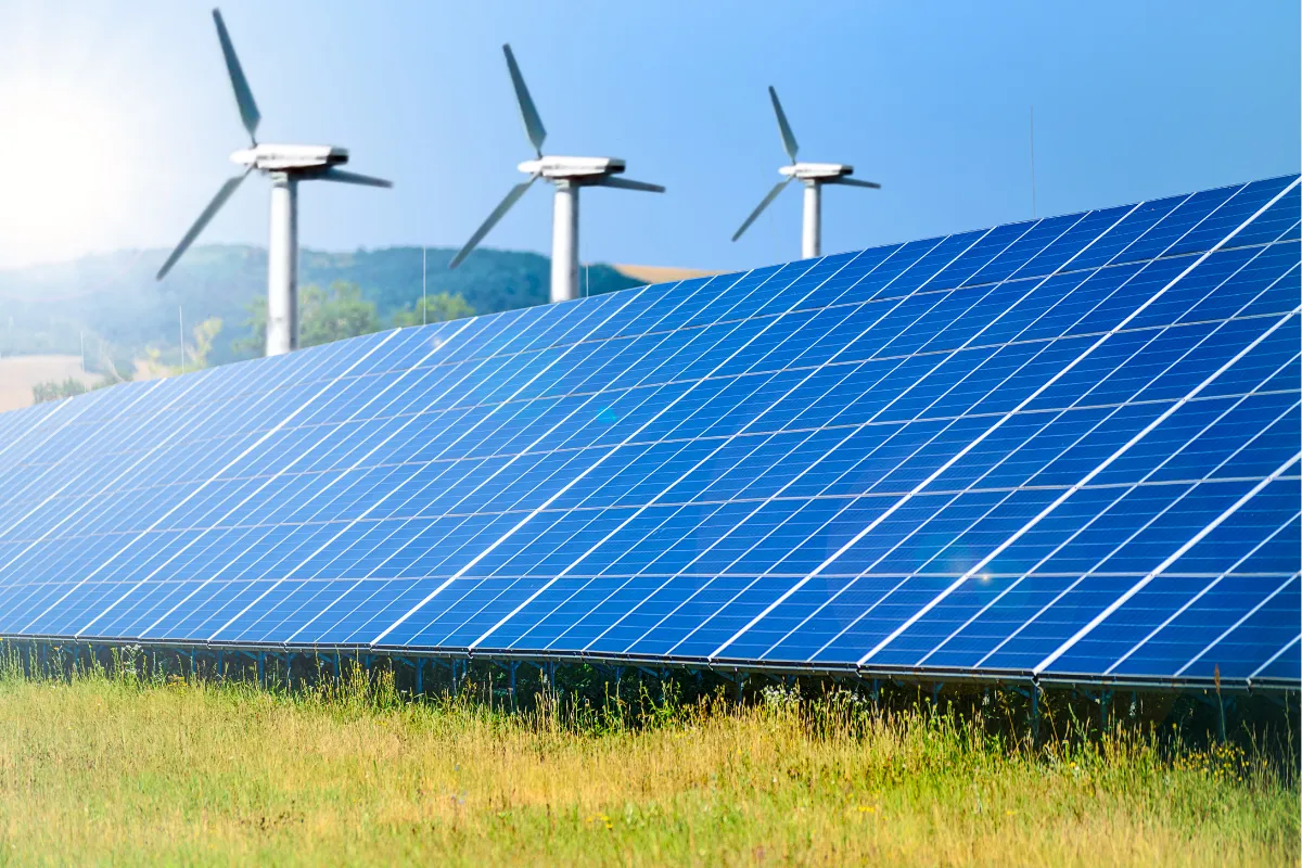 Photovoltaikanlage mit Solarmodulen und Windkraftanlagen auf einem Feld zur Darstellung erneuerbarer Energien.
